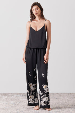 Woman wearing a silk jumpsuit hand painted on a black base - floral pattern 