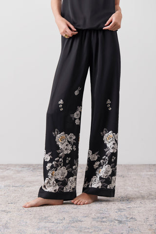 Details of a hand painted portion of a silk jumpsuit pants worn by a woman. 