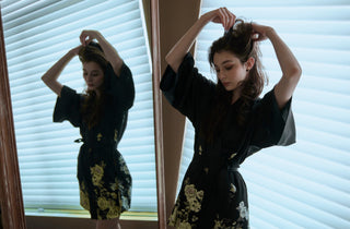 Woman in front of a mirror wearing a silk kimono and fixing her hair