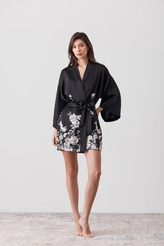 Woman standing in front of a white background wall wearing a silk short kimono