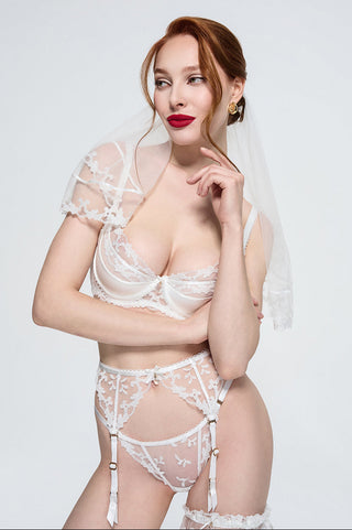 Woman wearing a white lace lingerie set on a plain background