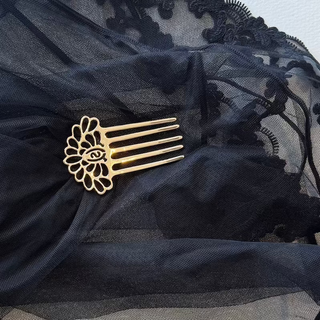 Black lace garment with a gold brooch on a wooden surface