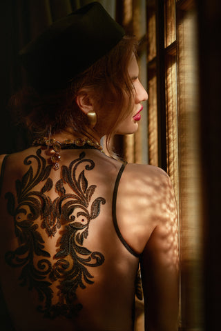 Woman wearing a bodysuit with a Devil like Tattoo on her back. 