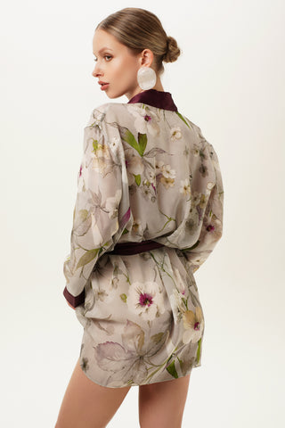 Back side of a woman wearing a floral silk kimono with a plain background