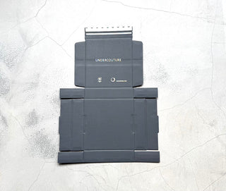 Two gray folding stands on a textured white surface with 'UNDERCOUTURE' branding.