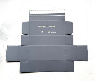 Gray packaging boxes with 'UNDERCOUTURE' branding on a light gray background
