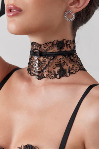 Woman wearing a black lace choker with a plain background